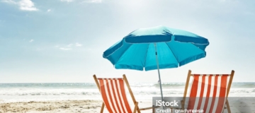 Still life shot of two deck chairs under an umbrella on the beach