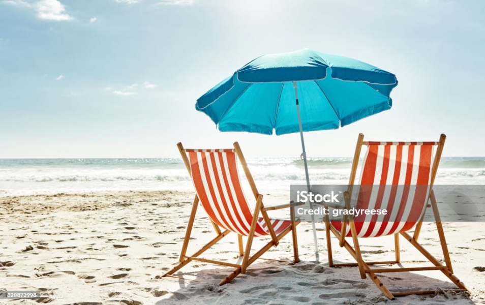 Still life shot of two deck chairs under an umbrella on the beach